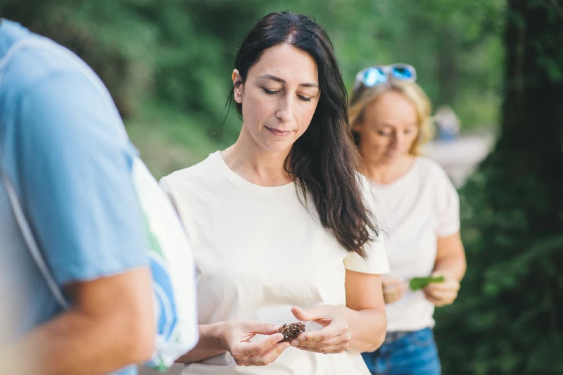 Frau steht drau&szlig;en in einer gruppe und schaut auf eine kastanie.