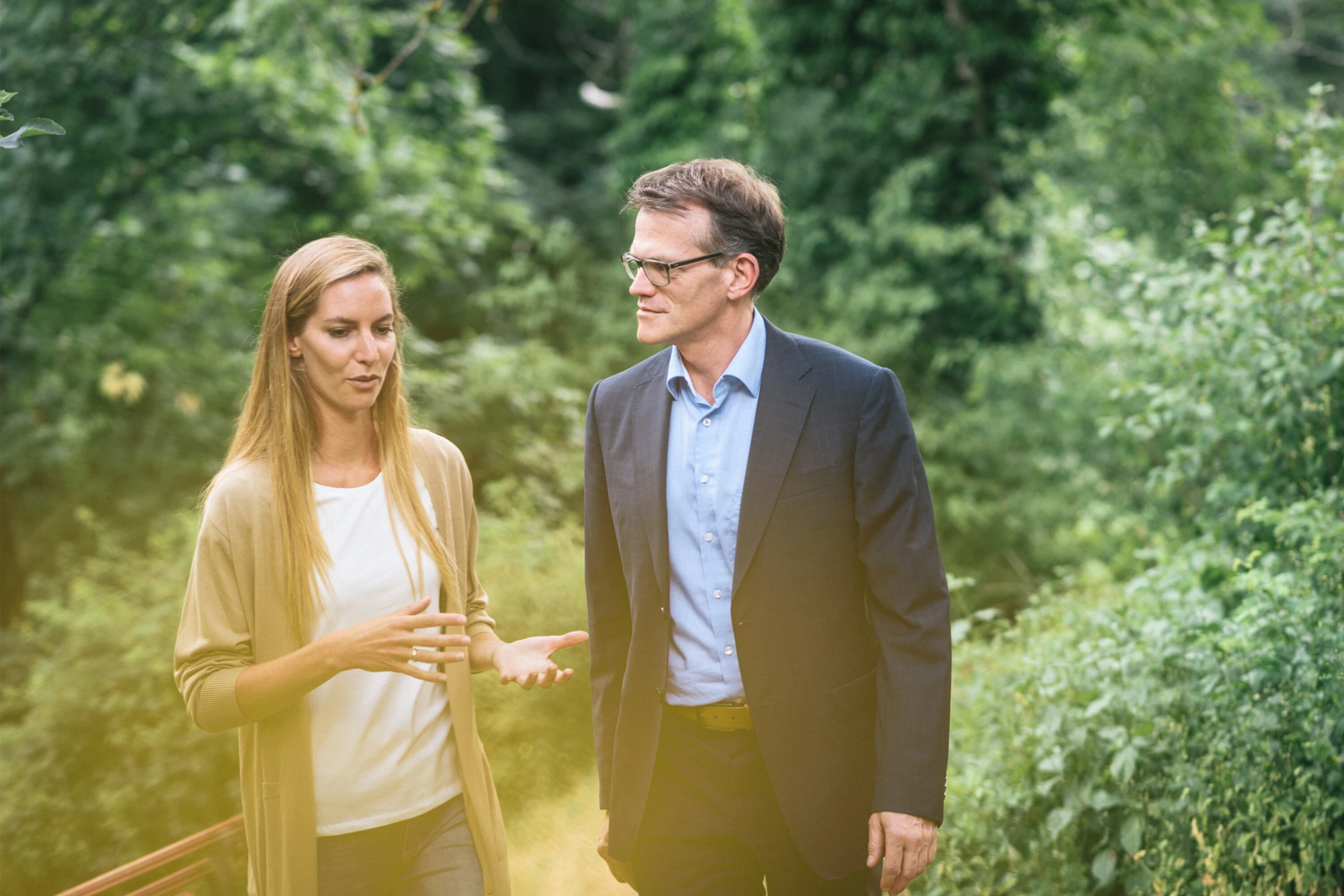 Mann in Anzug spaziert mit Frau im Wald und h&ouml;rt ihr zu